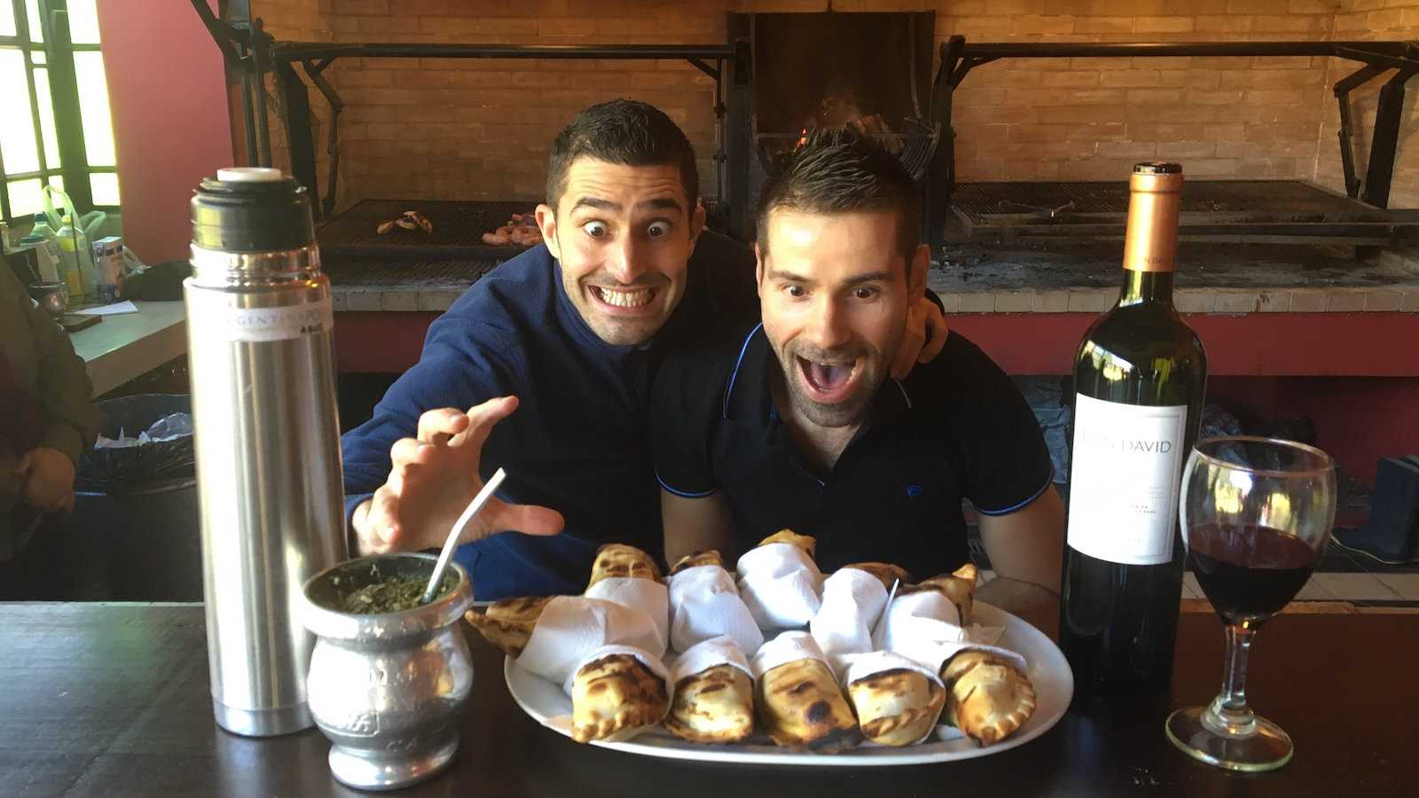 Gay couple about to eat Empanadas, wine, and maté at an Estancia near Buenos Aires.