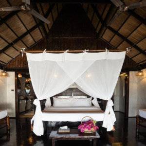 A big bed with white canopy in a room made of dark wood.