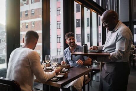 Seby and Stefan of Nomadic Boys laughing with a waiter at Fyn Restaurant.