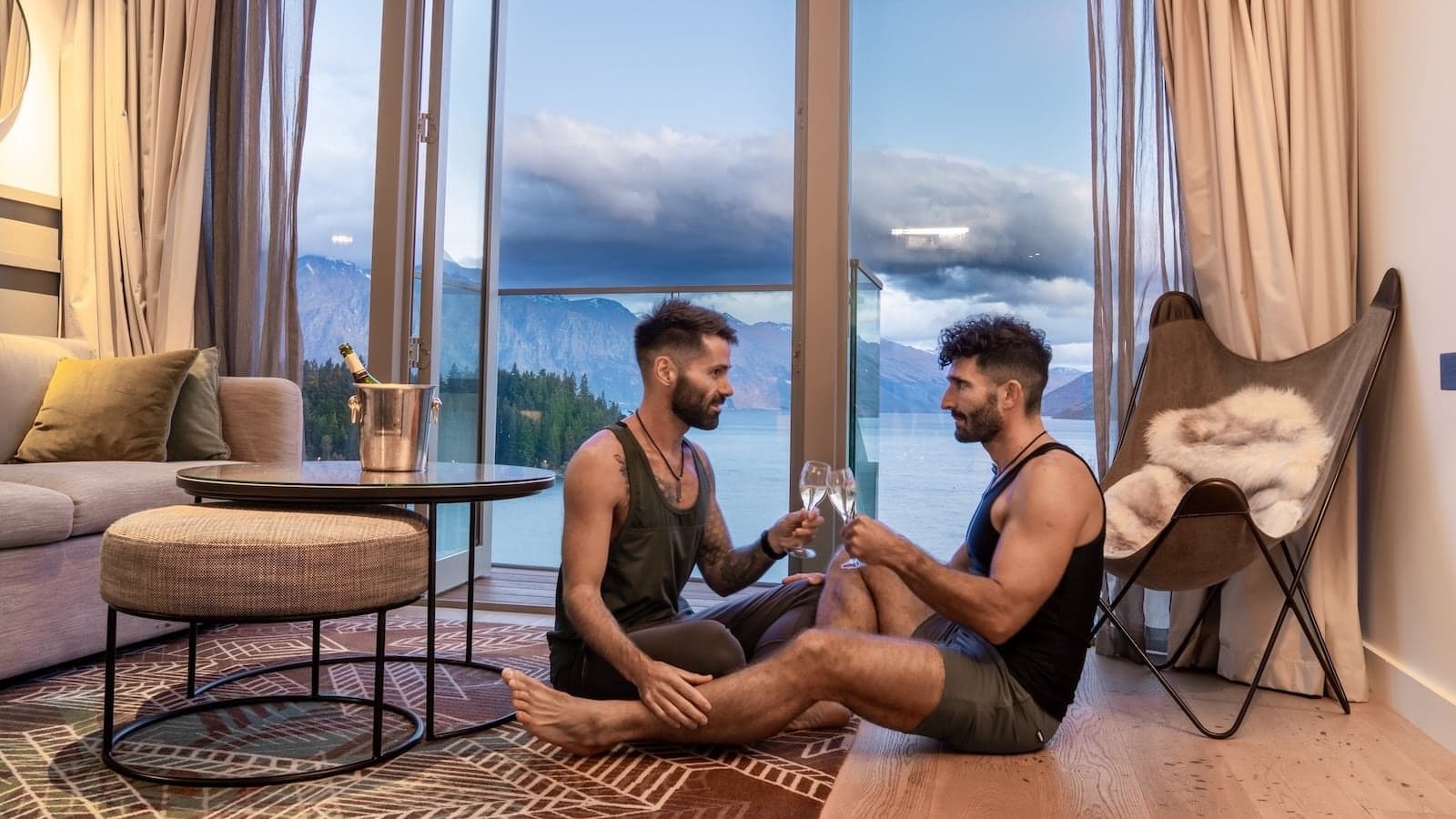 Gay couple Stefan and Seby on the floor drinking champagne at the QT Queenstown hotel in New Zealand.