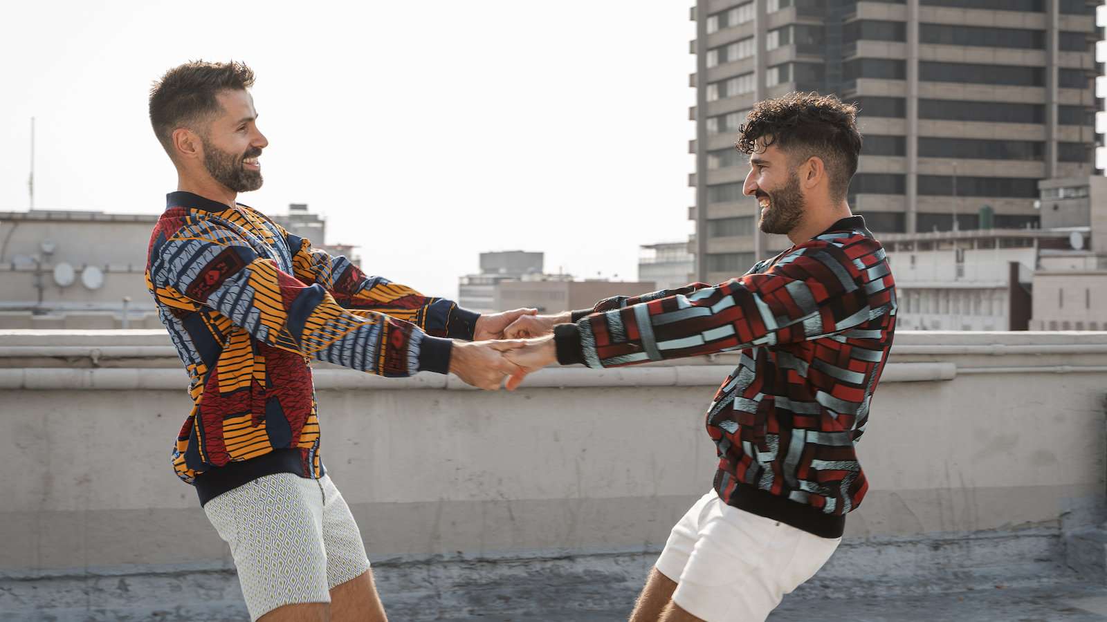 Seby and Stefan of Nomadic Boys holding hands and swinging on top of a rooftop in Johannesburg.