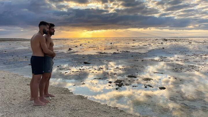 Gay couple on Lady Elliot Island beach at sunrise.