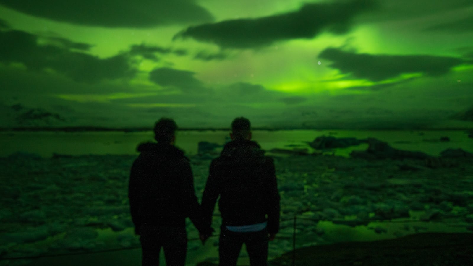 Gay couple watching Northern Lights together at Diamond Beach in Iceland.