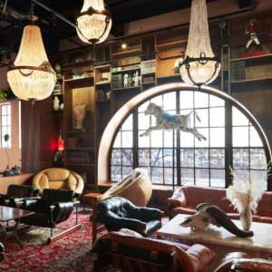 An eclectic sitting room with a big circular window, chandeliers and a horse figure hanging from the ceiling.