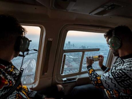 Nomadic Boys looking out the window of a helicopter and taking photos of Johannesburg from the sky.