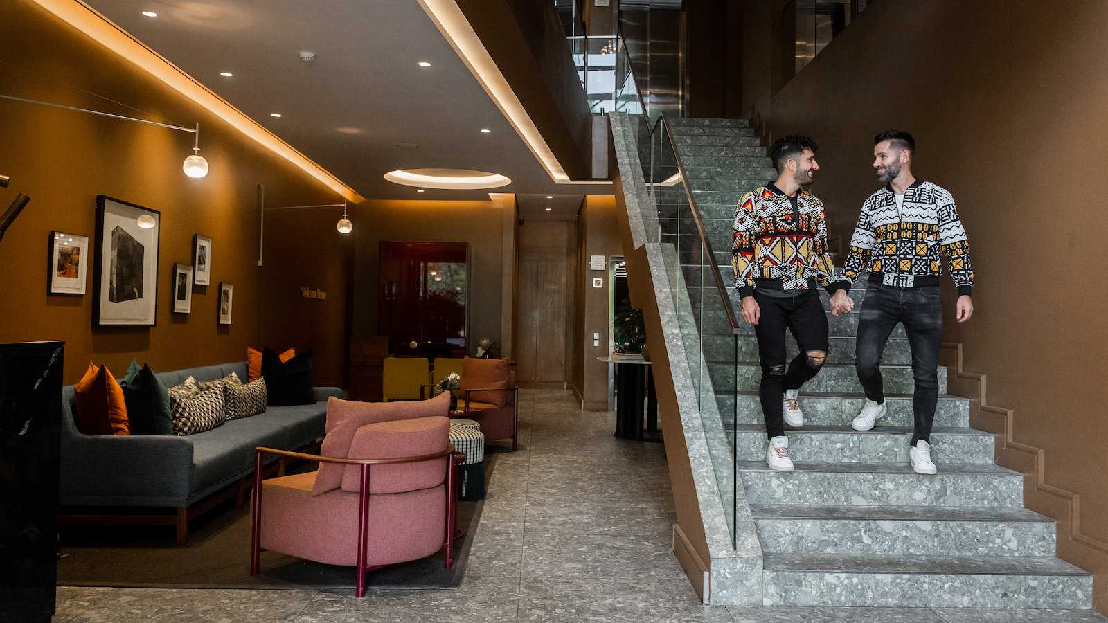 Seby and Stefan walking down the stairs inside gay hotel Home Suites Hotels Rosebank in Johannesburg.