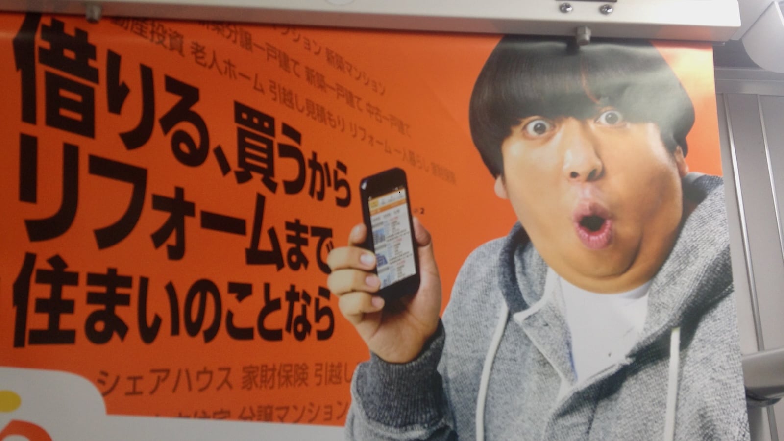 Japanese man with phone and shocked facial expression on the Tokyo Metro.