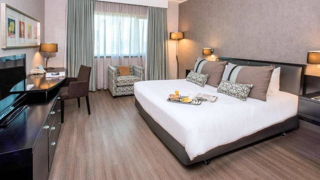 A spacious bedroom at the Mercure Santiago Centro with a breakfast tray sitting on the bed.