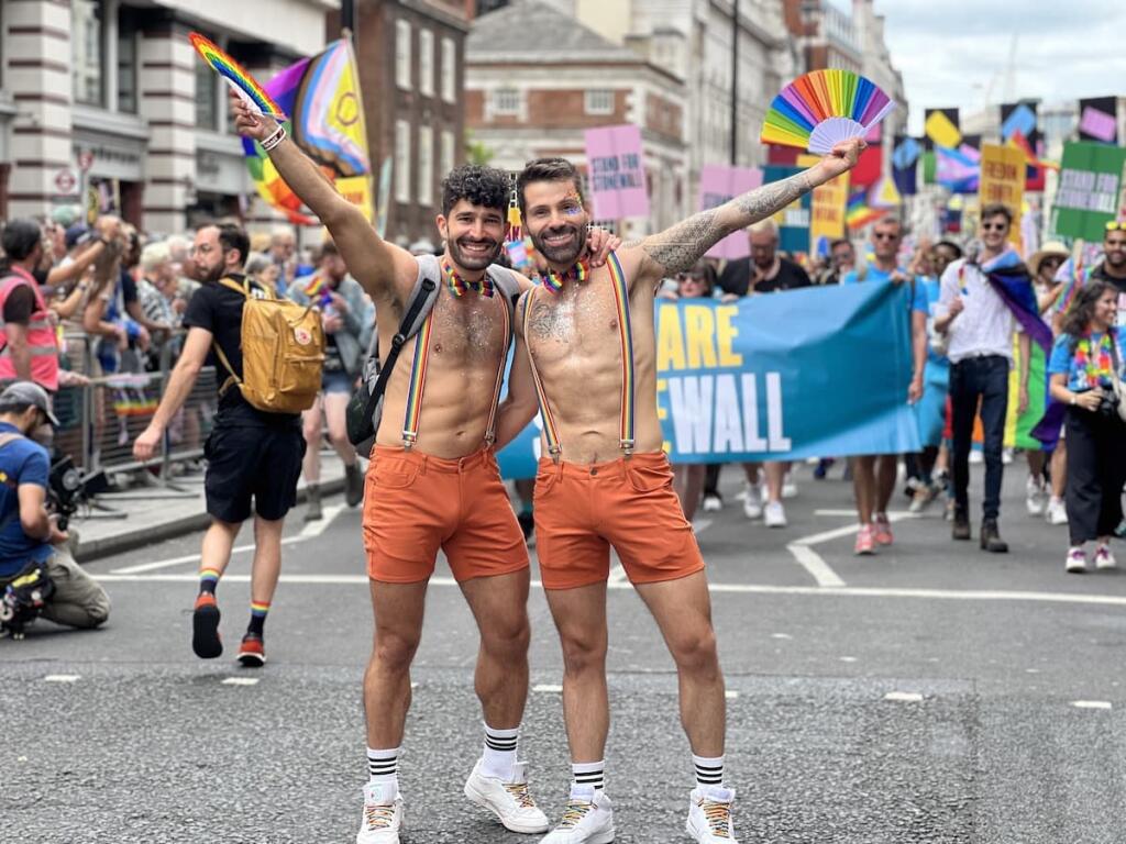 Gay couple waving rainbow flags at the London gay Pride Parade.