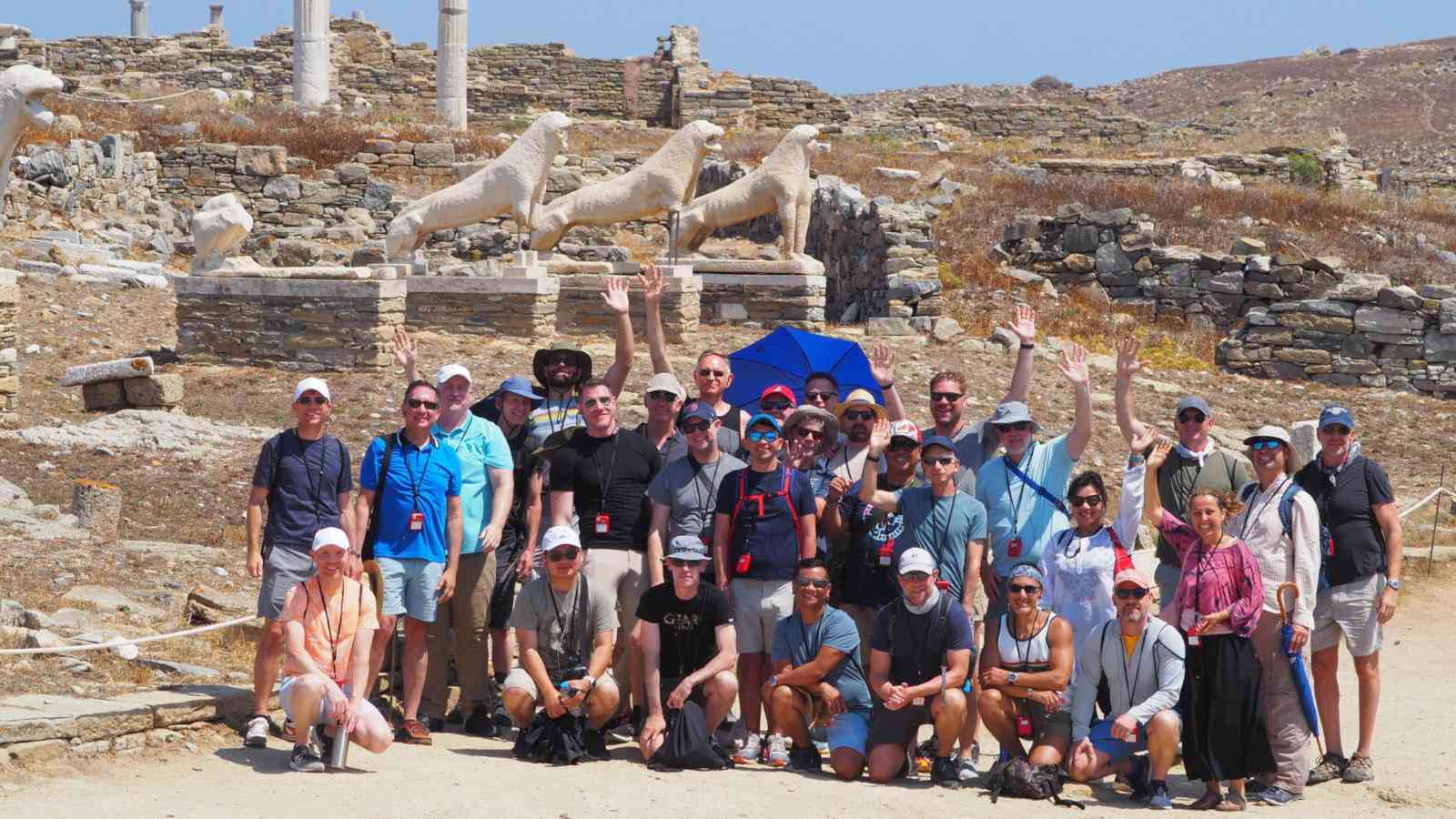 A large group of tourists posing in front of ruins on a dry island.