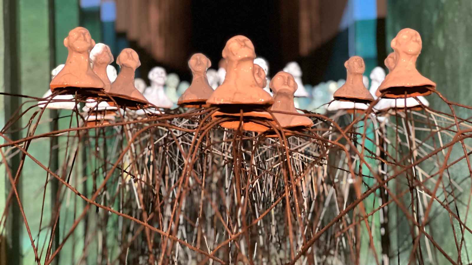 A close up of a sculpture showing vaguely human head and shoulders on long rusty-looking metal sticks.