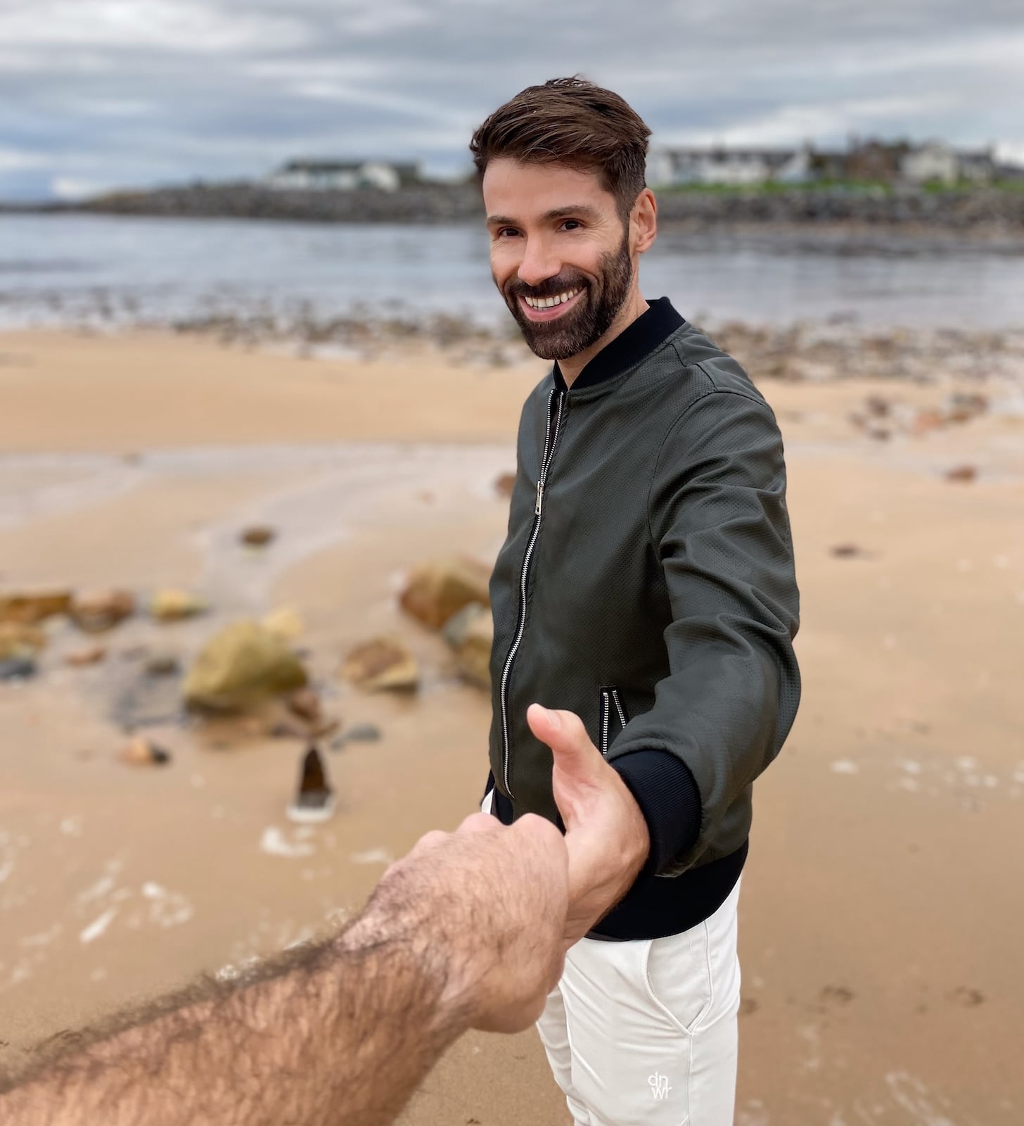 Seby reaching out holding Stefan's hand on Brora Beach in Scotland.