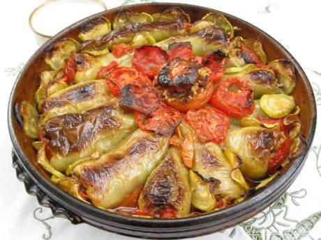 A round dish filled with peppers stuffed with tomatoes.